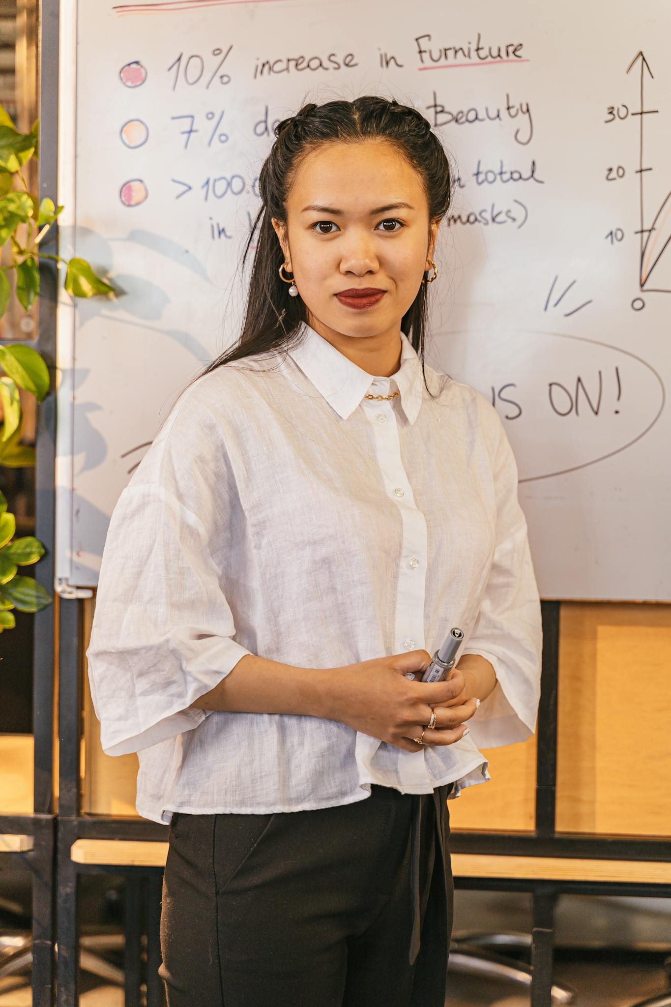 Young Asian businesswoman presenting ideas on a whiteboard during a workshop.